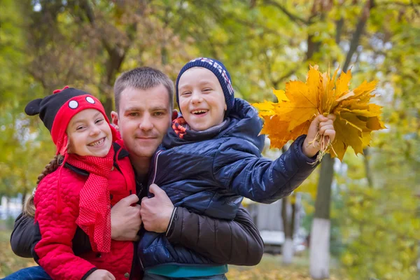 Vader met twee kinderen in herfst park — Stockfoto