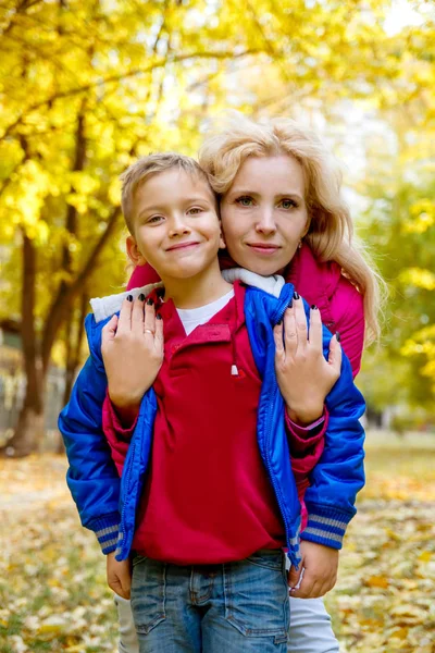 Mamma kramar son bland höstens park — Stockfoto
