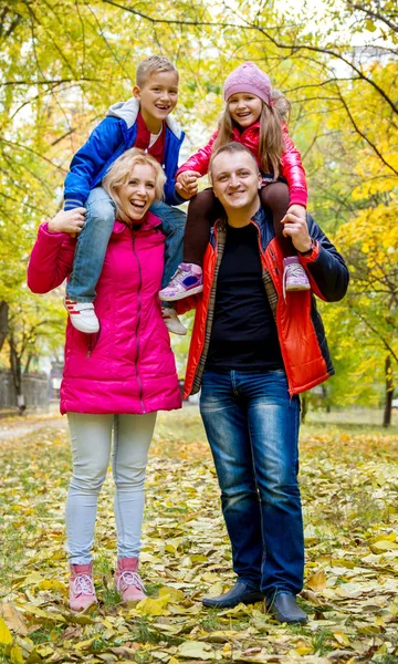 Mor och far bär två söta barn på axlarna — Stockfoto