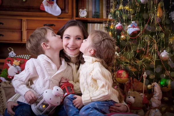 子供たちはクリスマス ツリーの下で母親にキス — ストック写真