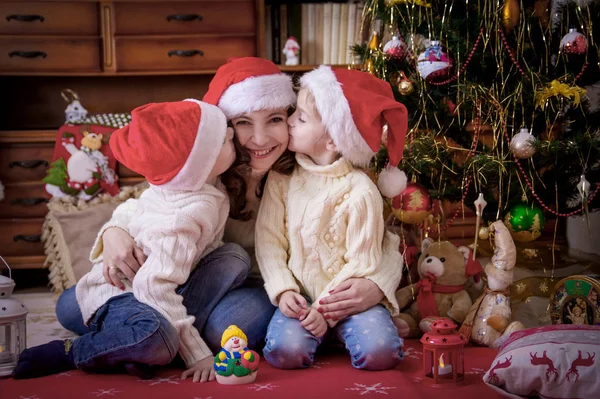 Kinderen it moeder kussen op de Wang onder kerstboom — Stockfoto