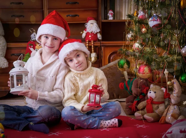 Wo children with lanterns under Christmas tree — Stock Photo, Image