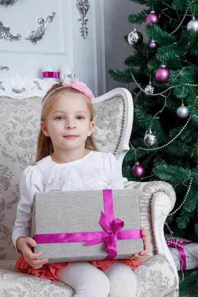 Κοπέλα που κρατά δώρο-κιβωτίων που κάθεται κάτω από το χριστουγεννιάτικο δέντρο — Φωτογραφία Αρχείου