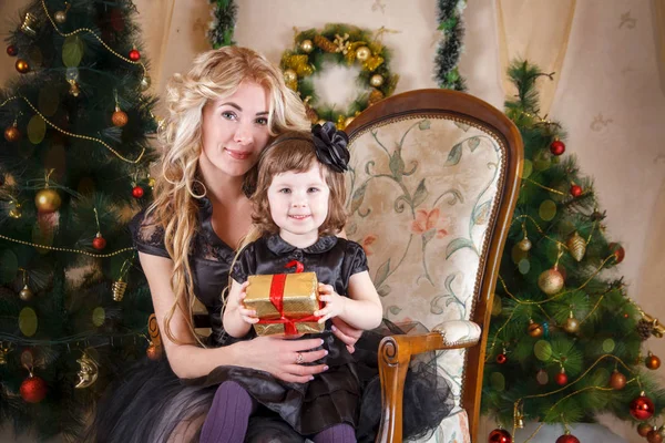 Mãe e filha sentadas debaixo da árvore de Natal — Fotografia de Stock