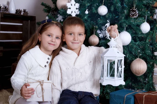 Dvě děti sedí s lucernami pod vánoční stromeček — Stock fotografie