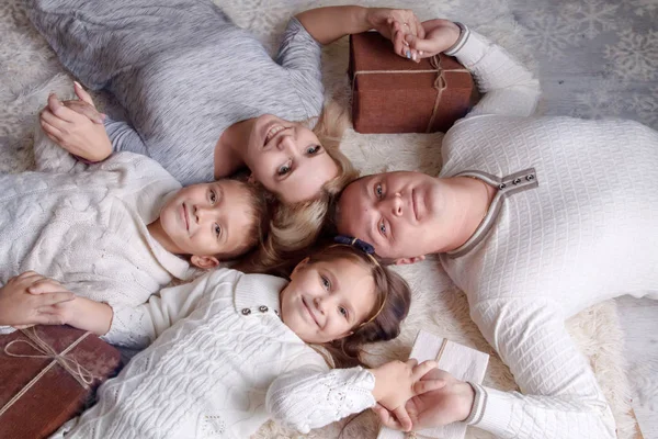 Familj med två barn och giftboxes liggande på golvet och lo — Stockfoto
