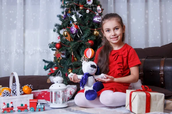 Dívka s plyš medvěd pod vánoční stromeček — Stock fotografie