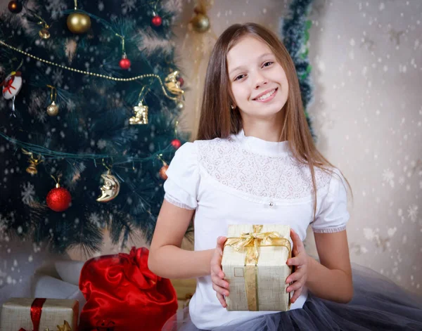 Girl holding gift box under Christmas tree — Stock Photo, Image