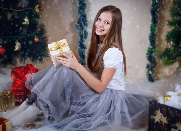 Menina sentada com caixa de presente sob a árvore de Natal — Fotografia de Stock