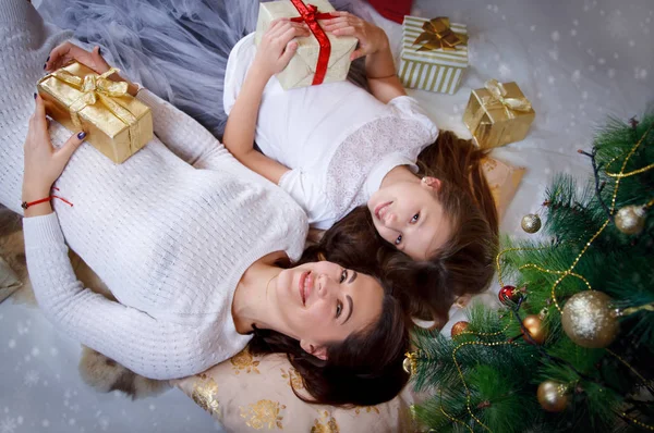 Mãe e filha deitada debaixo da árvore de Natal — Fotografia de Stock