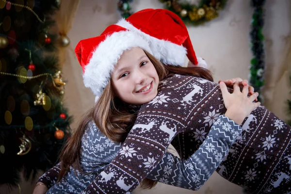 Mother hugging daughter under Christmas tree — Stock Photo, Image