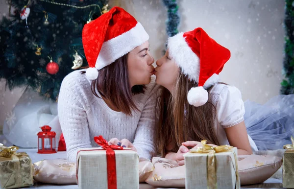 母と娘がキスをし、クリスマス ツリーの下で横になっています。 — ストック写真