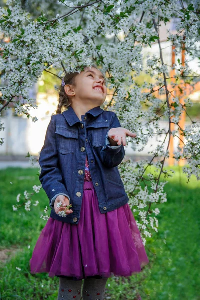 Flicka njuter flygande blomblad bland trädgård — Stockfoto