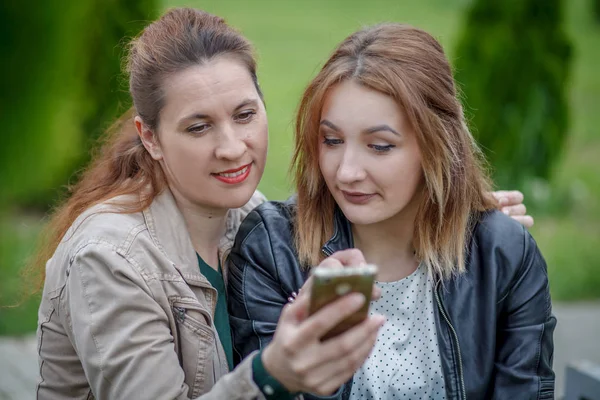 Due amiche che condividono social media in smart phone all'aperto — Foto Stock