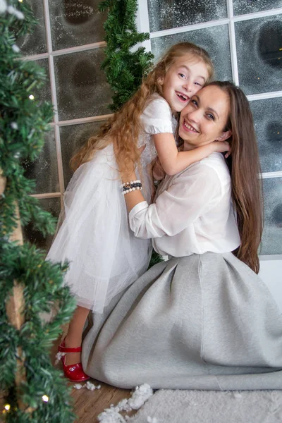 Mother and daughter in snowy winter studio hugging — Stock Photo, Image