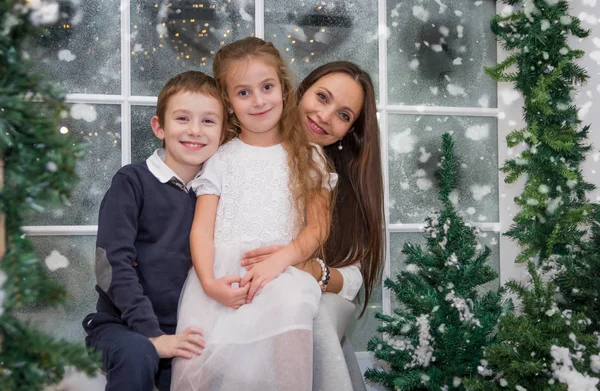 Mother with two children in snowy winter studio — Stock Photo, Image