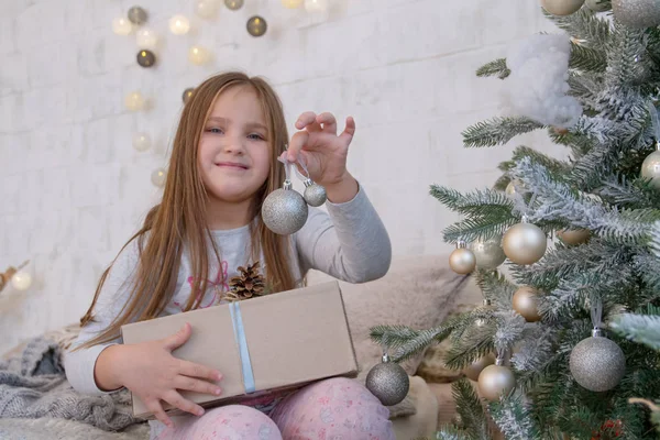 Chica bajo el árbol de Navidad con bola —  Fotos de Stock