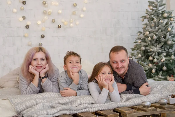Lycklig familj med två barn under julen träd liggande — Stockfoto