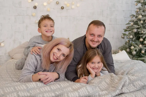 Família feliz com duas crianças sob a árvore de Natal deitado — Fotografia de Stock