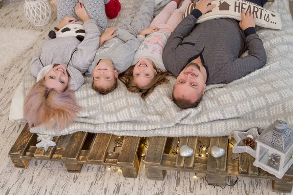 Lycklig familj med två barn liggande på sängen — Stockfoto