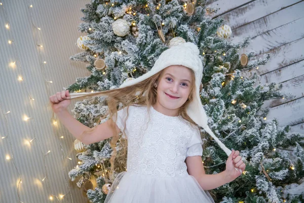 Meisje in witte hoed onder kerstboom — Stockfoto