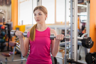 Spor salonunda halterleri kaldıran aktif bir kadın.