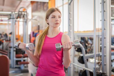 Spor salonunda halterleri kaldıran aktif bir kadın.