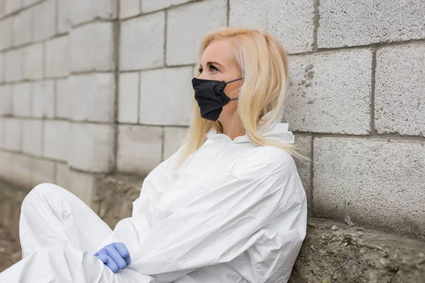 Mujer Con Máscara Negra Traje Protector Blanco Guantes Sentados Contra — Foto de Stock