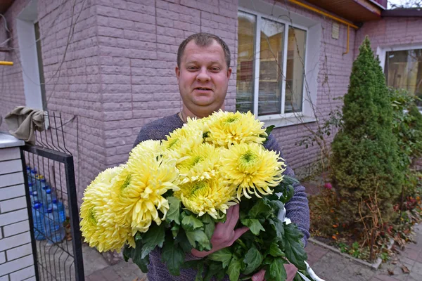 Adult mature man with flowers in his hands. At a birthday party.