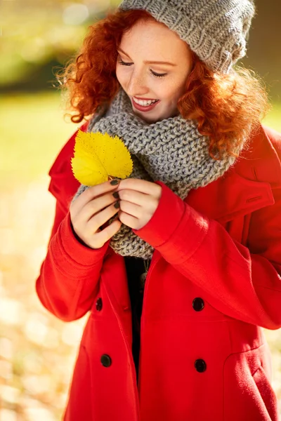 Улыбающаяся рыжая девушка выглядит желтым листом — стоковое фото