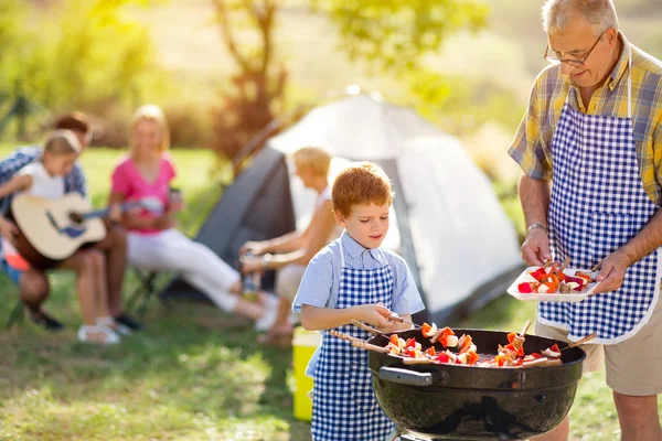 Família feliz grelhar carne em um churrasco — Fotografia de Stock