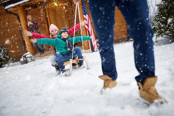 Gelukkige kinderen op slee in de winter dag - familie vakantie — Stockfoto