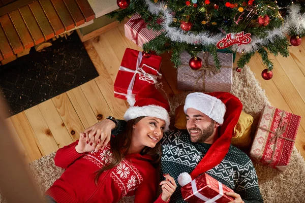 Casal apaixonado deitado sob a árvore de Natal — Fotografia de Stock