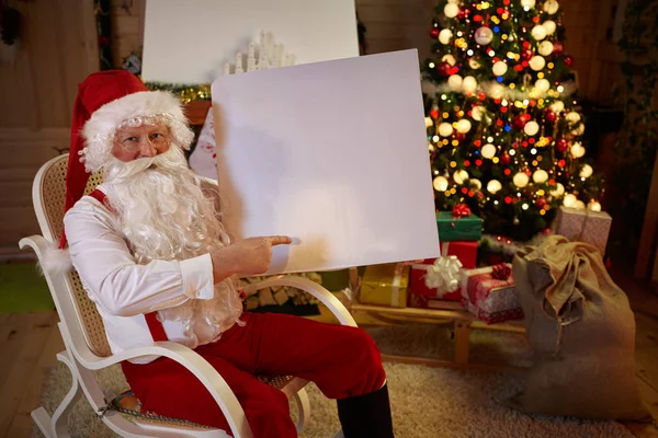 Weihnachtsmann zeigt auf weißes Banner — Stockfoto