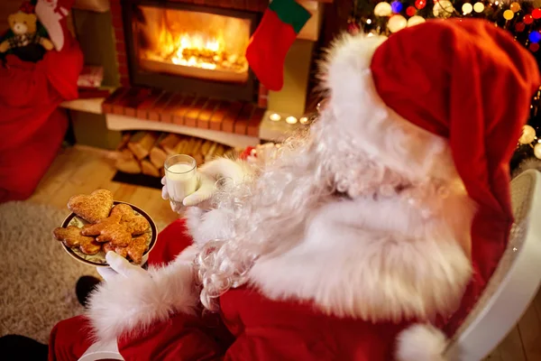 Santa Claus relajándose en casa con leche y galletas frescas —  Fotos de Stock