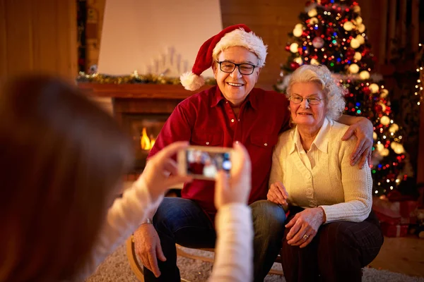 Дівчина зі смартфоном робить фотографії бабусь і дідусів на Різдво — стокове фото