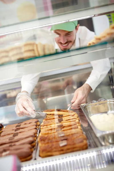 Работник пекарни достает торт из витрины — стоковое фото