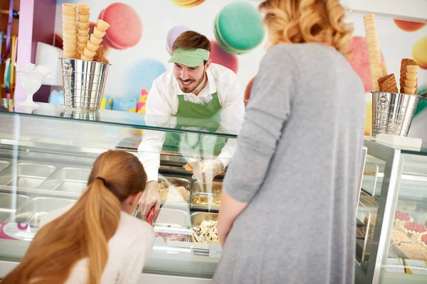 Vendor in confectionery serves girl with ice cream — Stock Photo, Image