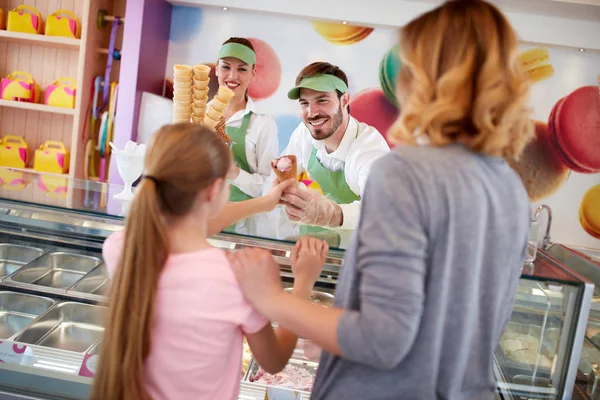 Affärsinnehavaren i konditori ger glass till flicka — Stockfoto