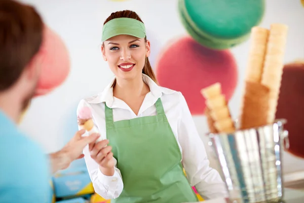 Travailleuse dans la confiserie donnant de la crème glacée au client — Photo