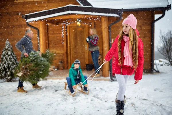 Familie genieten in de winter vooravond-kinderen rodelen — Stockfoto