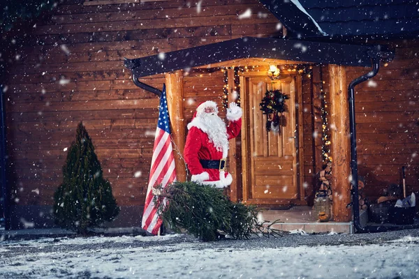 Papai Noel acenando na varanda da frente de sua casa de madeira — Fotografia de Stock