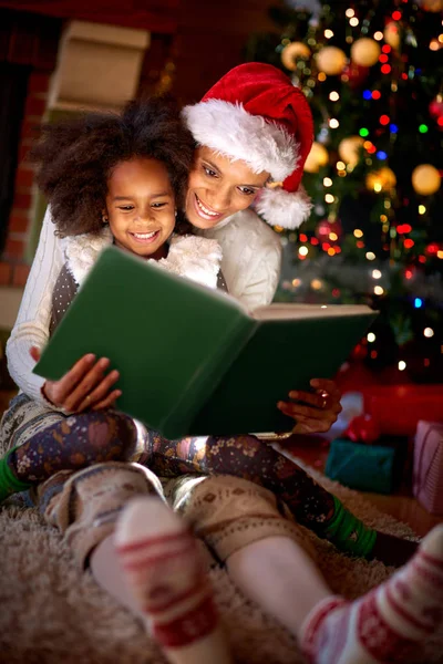 Мама читает книгу своей маленькой девочке в канун Рождества — стоковое фото