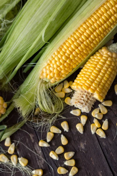 Fresh corn on cobs and corn grain on wooden table — Stock Photo, Image