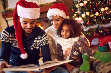 Mutlu afro Amerikan aile Noel günü şömine, bir kitap okumak