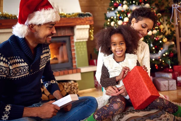 Милая чёрная девушка с родителями, открывающая рождественские подарки — стоковое фото
