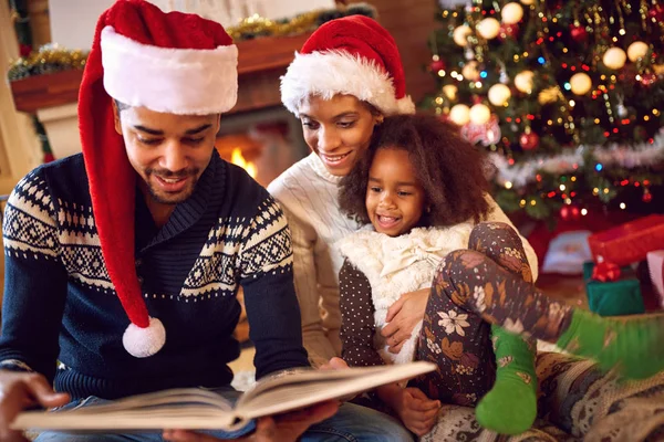 Feliz afro familia americana leer un libro en la chimenea en Navidad —  Fotos de Stock