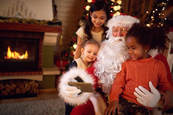 Papai Noel tirando selfie durante a atmosfera de Natal com crianças — Fotografia de Stock