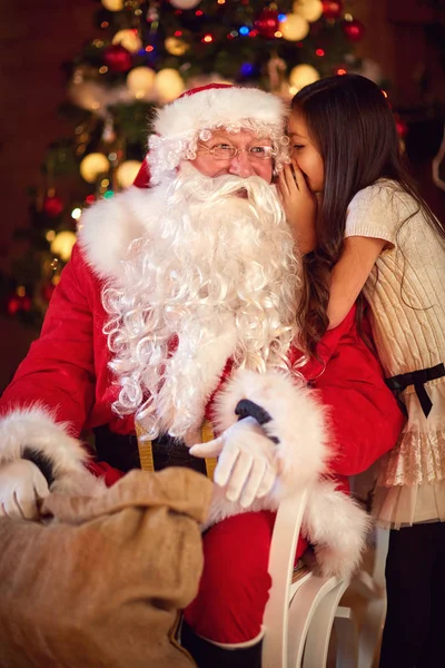 Girl whisper something to Santa Claus