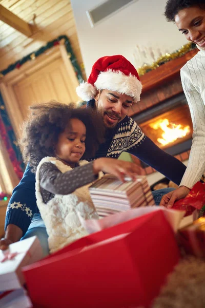 Mädchen mit ihren Eltern im Weihnachtsmorgen Eröffnungsgeschenk — Stockfoto